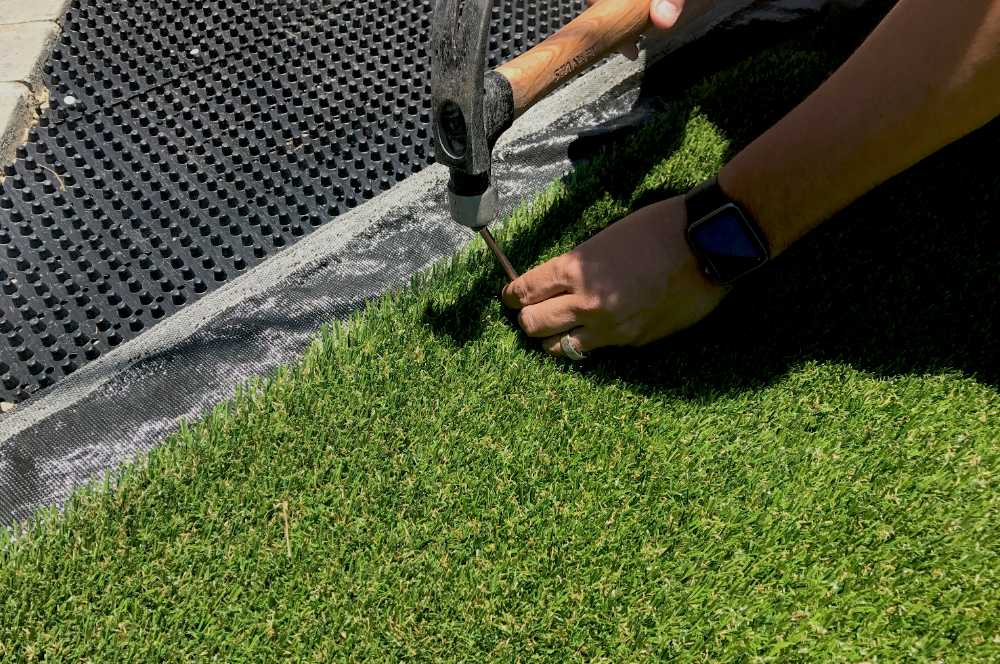 Turf edge nailed down along a drainage panel base during a Tampa installation